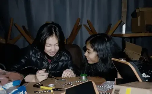 Two girls solderin a printed circut board